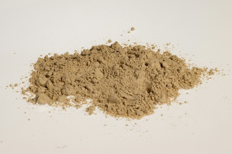 Pile of tan herbal root powder on a white surface