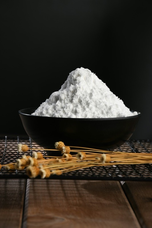 Mound of white powder in a black bowl against a dark background