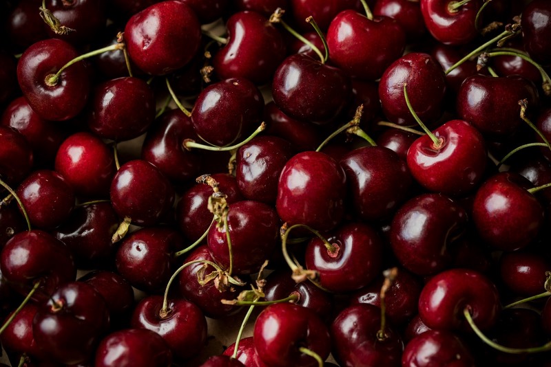 Dark red cherries with stems filling the frame