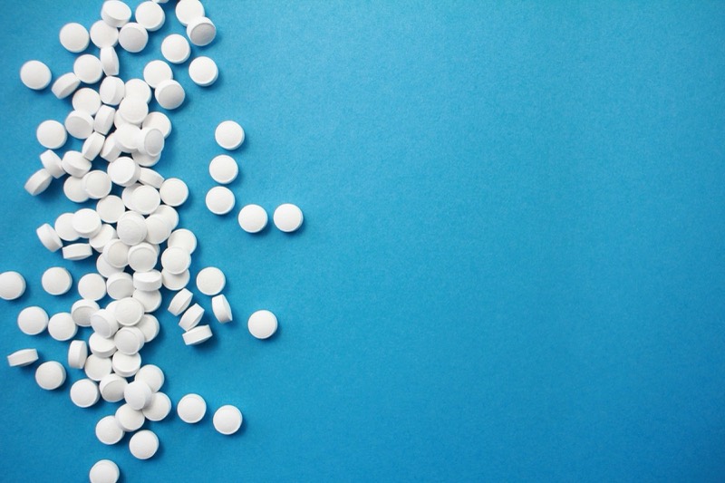 Round white tablets scattered along the left edge of a blue surface